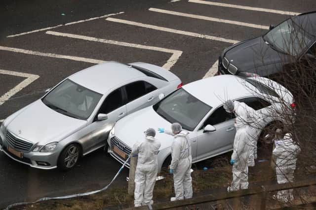 Police forensics officers examine a silver Audi with bullet holes in its windscreen at the scene. Picture: PA