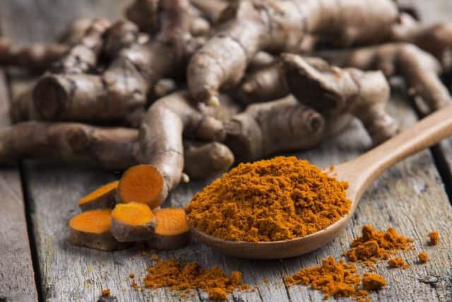 Pile of fresh turmeric roots on wooden table