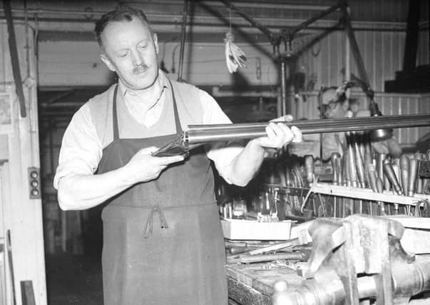 A foreman at John Dickson & Son holds a shotgun.