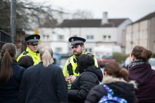 Police officers speak with parents outside the school in Penilee. Picture: John Devlin/TSPL