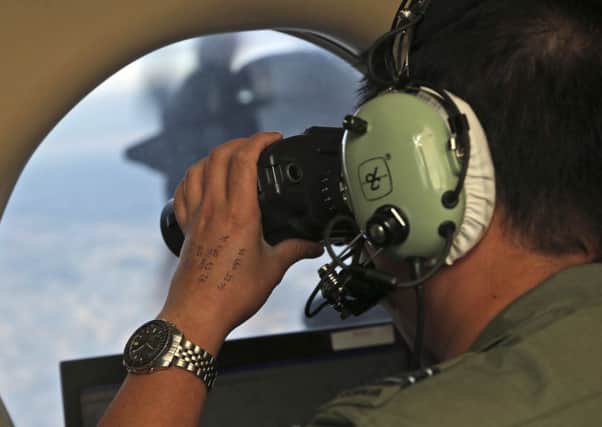 Flight Officer Jack Chen uses binoculars at an observers window on a Royal Australian Air Force P-3 Orion during the search for missing Malaysia Airlines Flight MH370 in Southern Indian Ocean, Australia. (AP Photo/Rob Griffith, File)