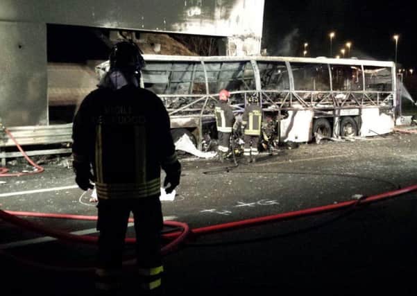 Firefighters inspect the wreck of the coach which burst into flames after crashing on a motorway near Verona. Picture: AP