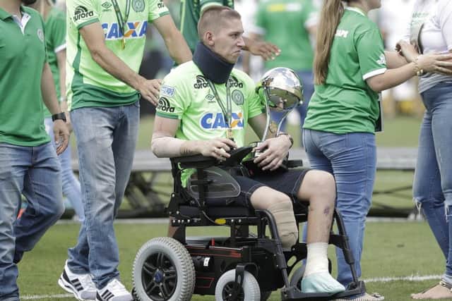 Chapecoense goalkeeper Jackson Follmann, one of the three players that survived the air crash almost two months ago, carries the Sudamericana trophy. Picture: Andre Penner/AP