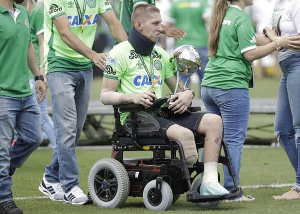 Chapecoense goalkeeper Jackson Follmann, one of the three players that survived the air crash almost two months ago, carries the Sudamericana trophy. Picture: Andre Penner/AP