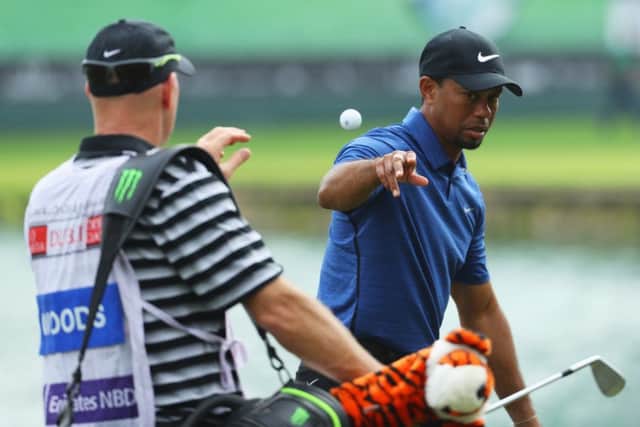 Tiger Woods tosses his golf ball to caddie Joe LaCava during a frustrating opening round in the Omega Dubai Desert Classic. Picture: Getty Images