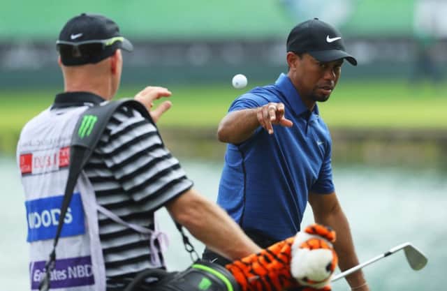 Tiger Woods tosses his golf ball to caddie Joe LaCava during a frustrating opening round in the Omega Dubai Desert Classic. Picture: Getty Images