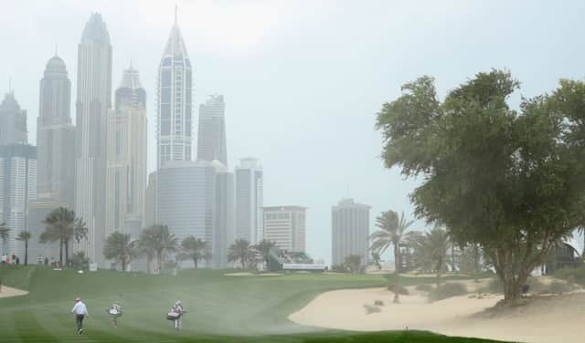Players walk up the eighth fairway as strong wind blows sand across the hole during the second round of the Omega Dubai Desert Classic. Picture: Getty Images