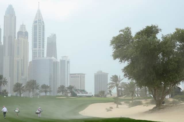 Players walk up the eighth fairway as strong wind blows sand across the hole during the second round of the Omega Dubai Desert Classic. Picture: Getty Images