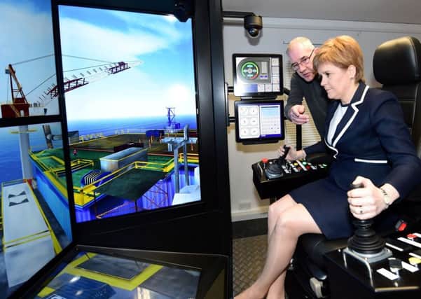 Trevor Dear, Training Centre Supervisor, shows First Minister Nicola Sturgeon how to use a crane simulator during a visit to Sparrows Training Centre, Tyrebagger, Aberdeen, as she announced a new Â£5 million fund to help Scottish-based firms benefit from the decommissioning of North Sea infrastructure. Picture: Kami Thomson/PA Wire