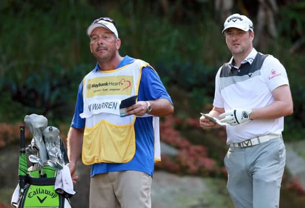 Marc Warren ponders a tee shot with his caddie Ken Herring en route to a nine-under-par opening round in the Maybank Championship. Picture: Getty Images