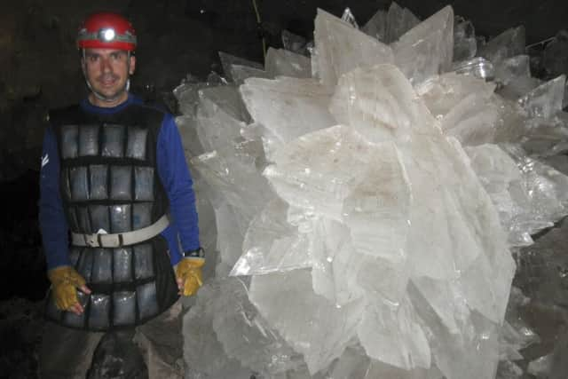 In this image provided by Mike Spilde, Mario Corsalini stands near to a gypsum rosette crystal. In a Mexican cave system so beautiful and hot that it is called both Fairyland and hell, scientists have discovered life trapped in crystals that could be 50,000 years old. The bizarre and ancient microbes were found dormant in caves in Naica, Mexico, and were able to exist by living on minerals such as iron and manganese, said Penelope Boston, head of NASA's Astrobiology Institute. (Mike Spilde via AP)