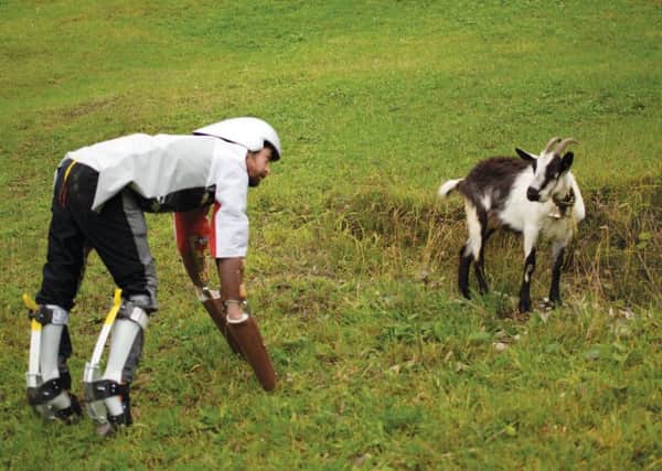 Thomas Thwaites wears prosthetic legs as he interacts with a goat on the slopes of Wolfenschiessen
