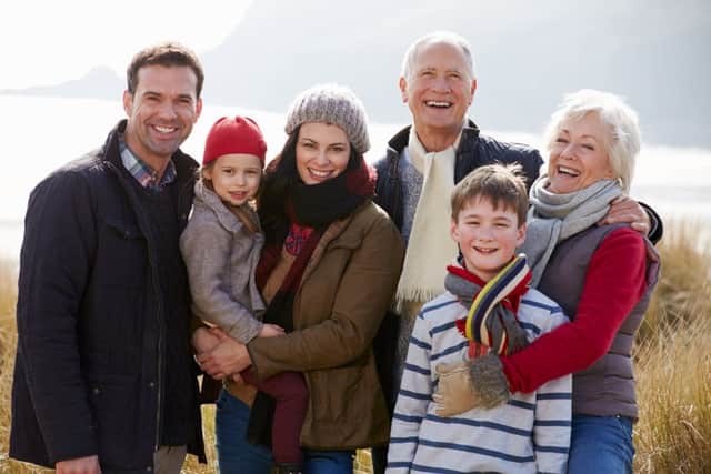 Multi Generation Family In Sand Dunes On Winter Beach Smiling