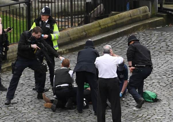 A policeman points a gun at a man on the floor at the top of the frame as emergency services attend the scene outside the Palace of Westminster. Picture: PA
