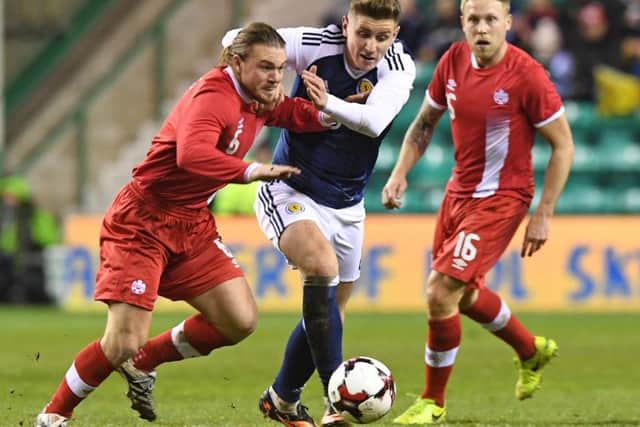 Scotland's Tom Cairney, centre, battles with Canada's Samuel Piette. Picture: SNS