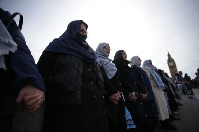 Women activists wearing blue hold hands on Westminster Bridge in front of the Houses of Parliament to honour the victims of the March 22 attack in central London on March 26, 2017. / AFP PHOTO / Daniel LEAL-OLIVAS (Photo credit should read DANIEL LEAL-OLIVAS/AFP/Getty Images)