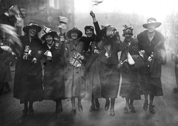 A group of women celebrate by waving Union Jacks on Armistice Day. Picture: Topical Press Agency/Getty Images.