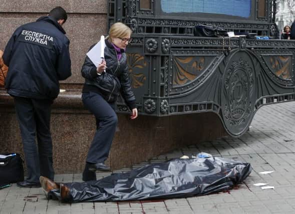 Forensic experts and police officers work at the scene following the killing of Denis Voronenko in Kiev, Ukraine  (AP Photo/Sergei Chuzavkov)