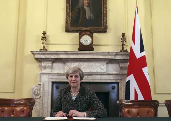 Britain's Prime Minister Theresa May, sitting below a painting of Britain's first Prime Minister Robert Walpole, signs the official letter to European Council President Donald Tusk. Picture AP