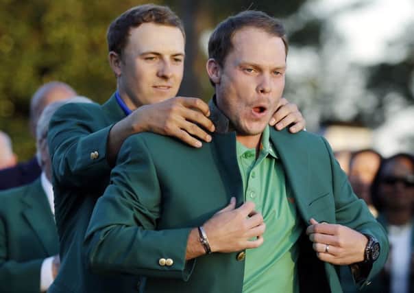 The magical moment when Masters winner Danny Willett is helped on with the green jacket by 2015 champion Jordan Spieth. Picture: Chris Carlson/AP