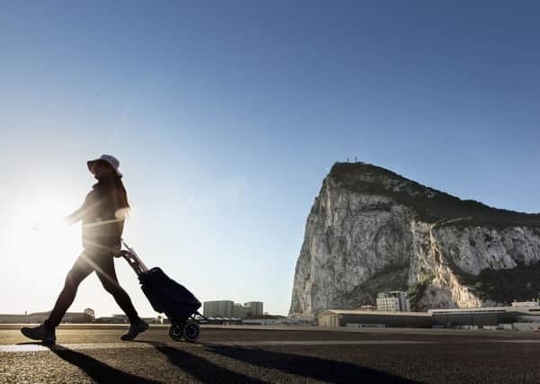 A woman walks on the Spanish side of the border between Spain and the British overseas territory of Gibraltar with the iconic Rock of Gibraltar in the background. Picture: AP Photo/Daniel Ochoa de Olza