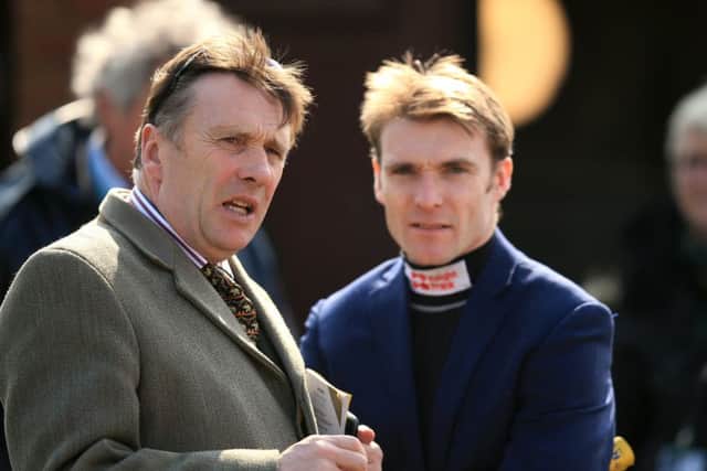 Peter Scudamore chats with his son Tom, who rides the joint-favourite in tomorrows Grand National. Picture: PA.