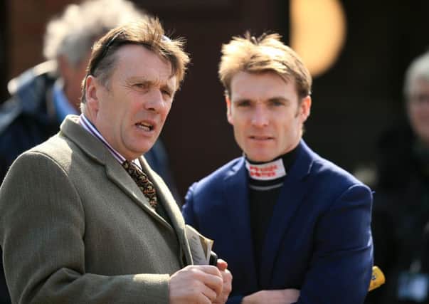 Peter Scudamore chats with his son Tom, who rides the joint-favourite in tomorrows Grand National. Picture: PA.