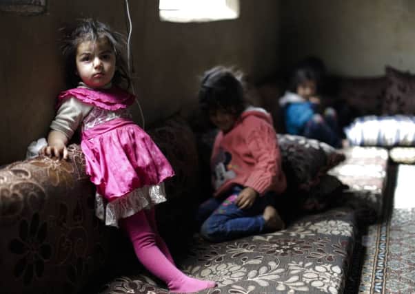 Syrian refugee children watch television in their parents tent at an informal refugee camp in Bekaa valley, Lebanon. Picture: AP