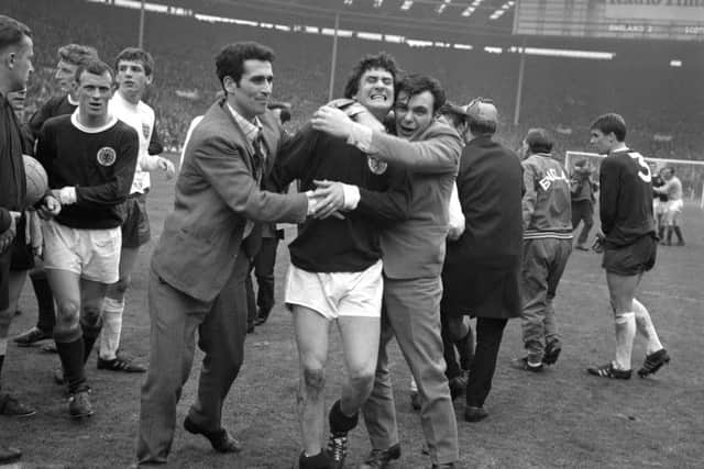 Scotland's Jim Baxter is hugged by fans who invaded the pitch at Wembley following the 3-2 victory over England. Picture: PA