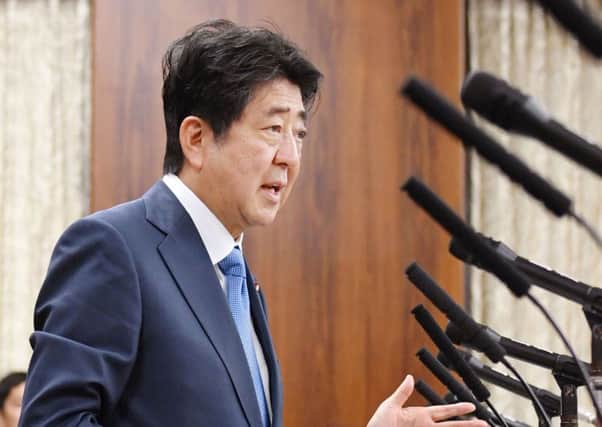 Japanese Prime Minister Shinzo Abe speaks in front of a line of microphones at a parliamentary panel on national security and diplomacy at parliament's upper house in Tokyo. (Yoshinobu Shimizu/Kyodo News via AP)