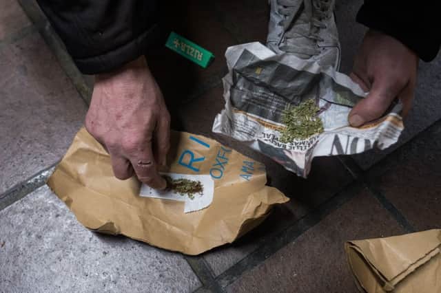 A homeless person rolls up Spice, a synthetic cannabis substitute, into a cigarette