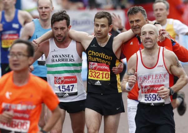 A runner is helped near the finish line during the London marathon. Picture: Getty