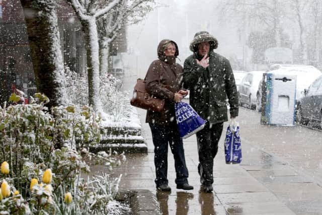 People walk through a snow shower along Grampian Road in Aviemore. Picture: PA