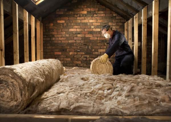 Man laying loft insulation to make the home more energy efficient