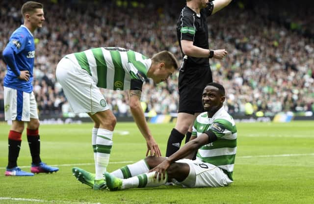 Moussa Dembele (right) sits on the ground after pulling up with an injury during the semi-final win over Rangers. Picture: SNS
