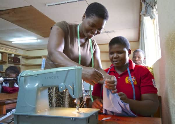 Child learning to use a sewing machine in Malawi