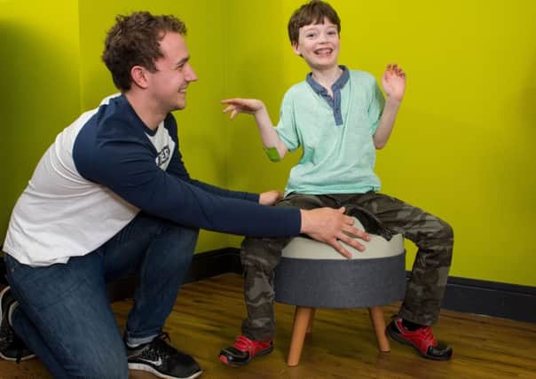 Callum Hunter helps Cammy Lamont try out the calming chair he designed for children with autism.