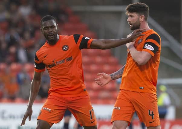 Wato Kuate, left, clashes with Dundee United team-mate Mark Durnan as he is substituted in the first leg of the Premiership play-off final. Picture: SNS
