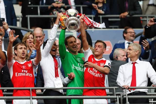 Arsene Wenger looks on as Gabriel, goalkeeper Petr Cech and Mesut Ozil lift up the FA Cup. Photograph: Adrian Dennis/AFP/Getty