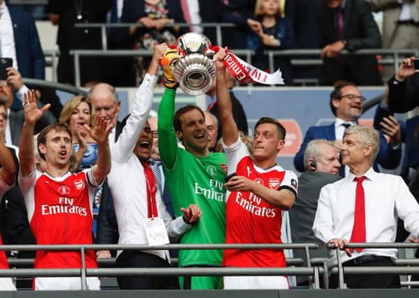 Arsene Wenger looks on as Gabriel, goalkeeper Petr Cech and Mesut Ozil lift up the FA Cup. Photograph: Adrian Dennis/AFP/Getty