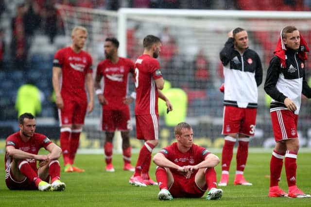 Aberdeens sit despondently on the pitch but gave a performance their fans could be proud of. Photograph: SNS