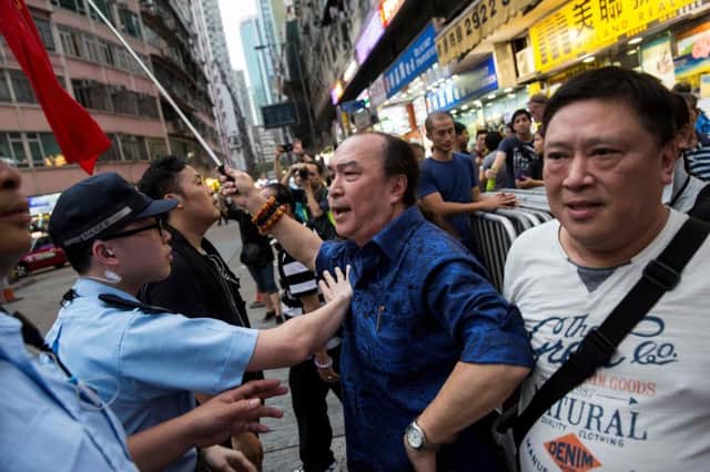 A pro-Beijing supporter waving Chinese flags is held back by police as he tries to argue with pro-democracy activists (not pictured) gathering for a candlelight vigil in Hong Kong to mark the 28th anniversary of the 1989 Tiananmen crackdown in Beijing. Picture: ISAAC LAWRENCE/AFP/Getty Images