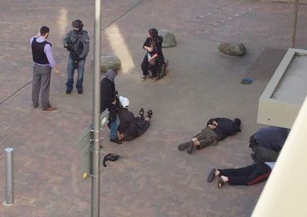 People (right) lie on the ground after being detained by police at Elizabeth Fry flats in Barking, east London. Picture: PA