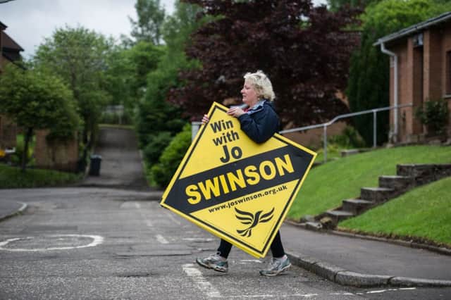 A Lib Dem activist in Milngavie carries a sign supporting the party's East Dunbartonshire candidate, Jo Swinson. Picture: John Devlin/TSPL