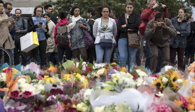Members of the public gather near flowers on the South side of London Bridge, close to Borough Market in London in tribute to the victims of the June 3 attacks. Picture: Dan Kitwood/Getty Images
