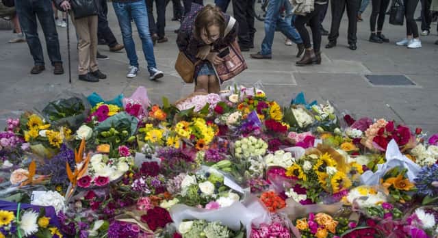 Members of the public gather near flowers on the South side of London Bridge, close to Borough Market in London to pay tribute to the victims of the June 3 attacks. Picture: Dan Kitwood/Getty Images