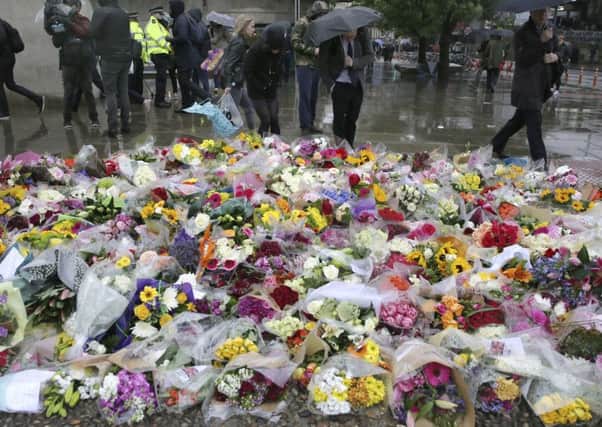 Pedestrians walk by a flower memorial in the London Bridge.(AP Photo/Tim Ireland)