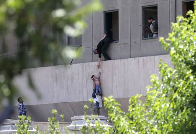 Iranian policemen evacuate a child from the parliament building in Tehran during an attack on the complex by the Islamic State group. Picture: OMID VAHABZADEH/AFP/Getty Images