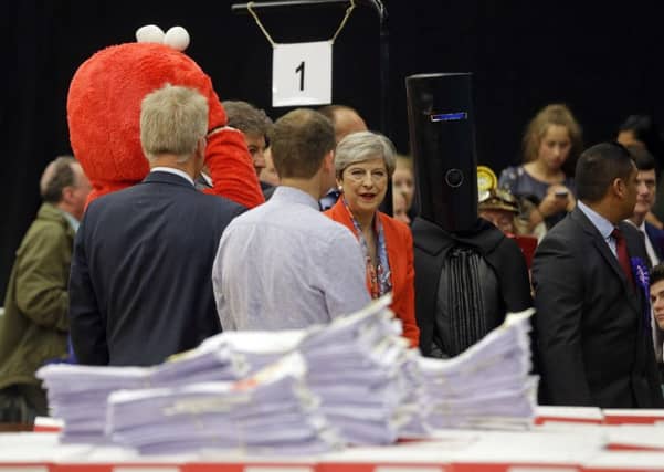 Britain's Prime Minister Theresa May, center, stands next to candidate 'Lord Buckethead' in Maidenhead (AP Photo/Alastair Grant)