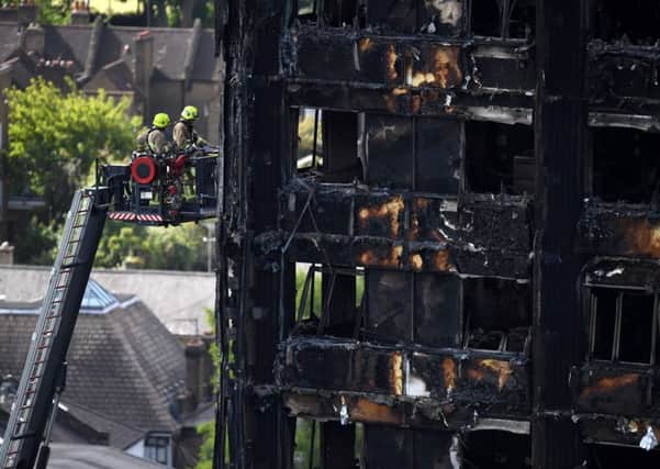 Firefighters perched on an extendable ladder inspect the remains of Grenfell Tower. Picture: Getty